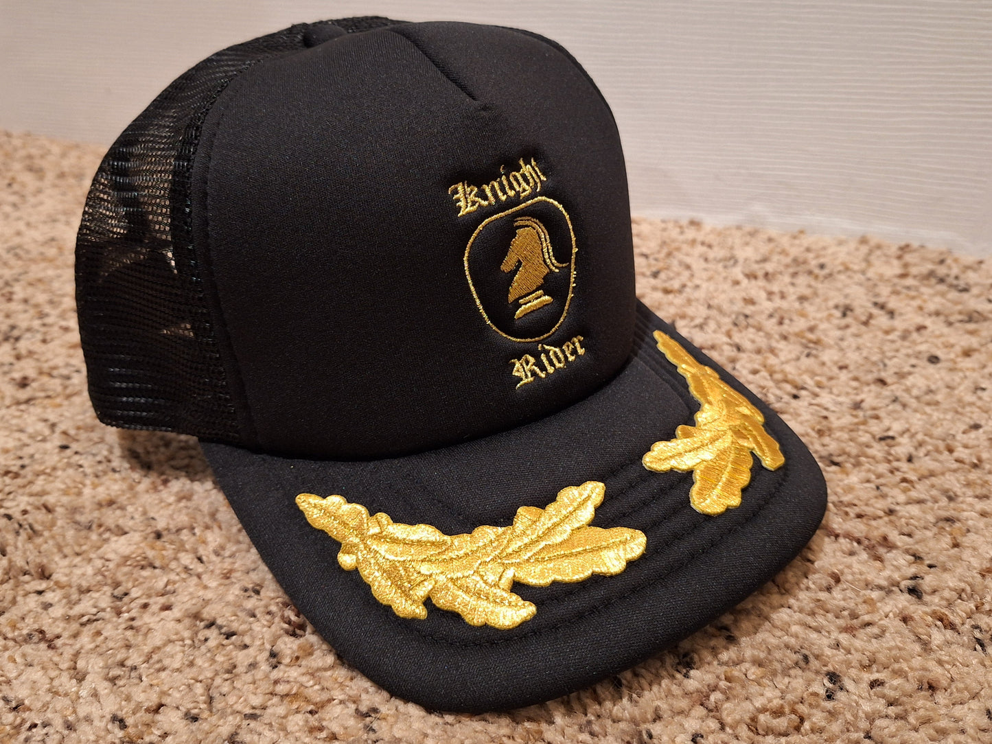 Black cap with gold embroidery on a beige carpet